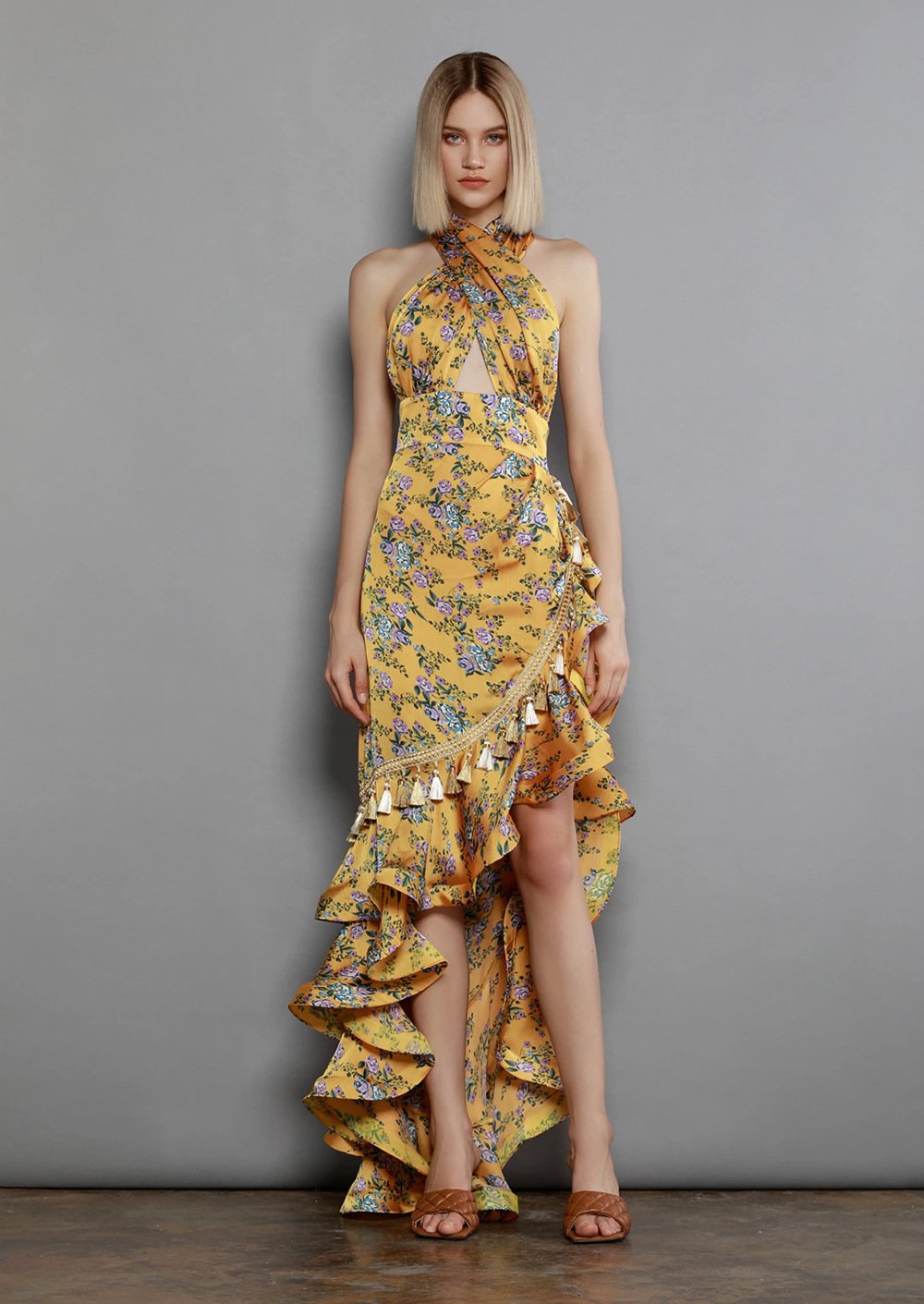 Woman wearing a yellow floral dress against a gray background