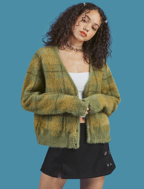 Woman wearing a green plaid cardigan on a blue background