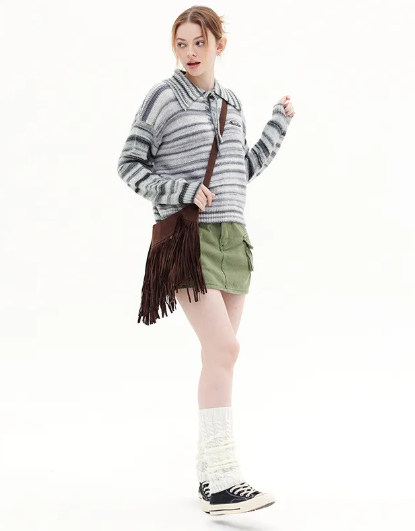 Person wearing a striped sweater, green shorts, and white socks with black shoes on a white background