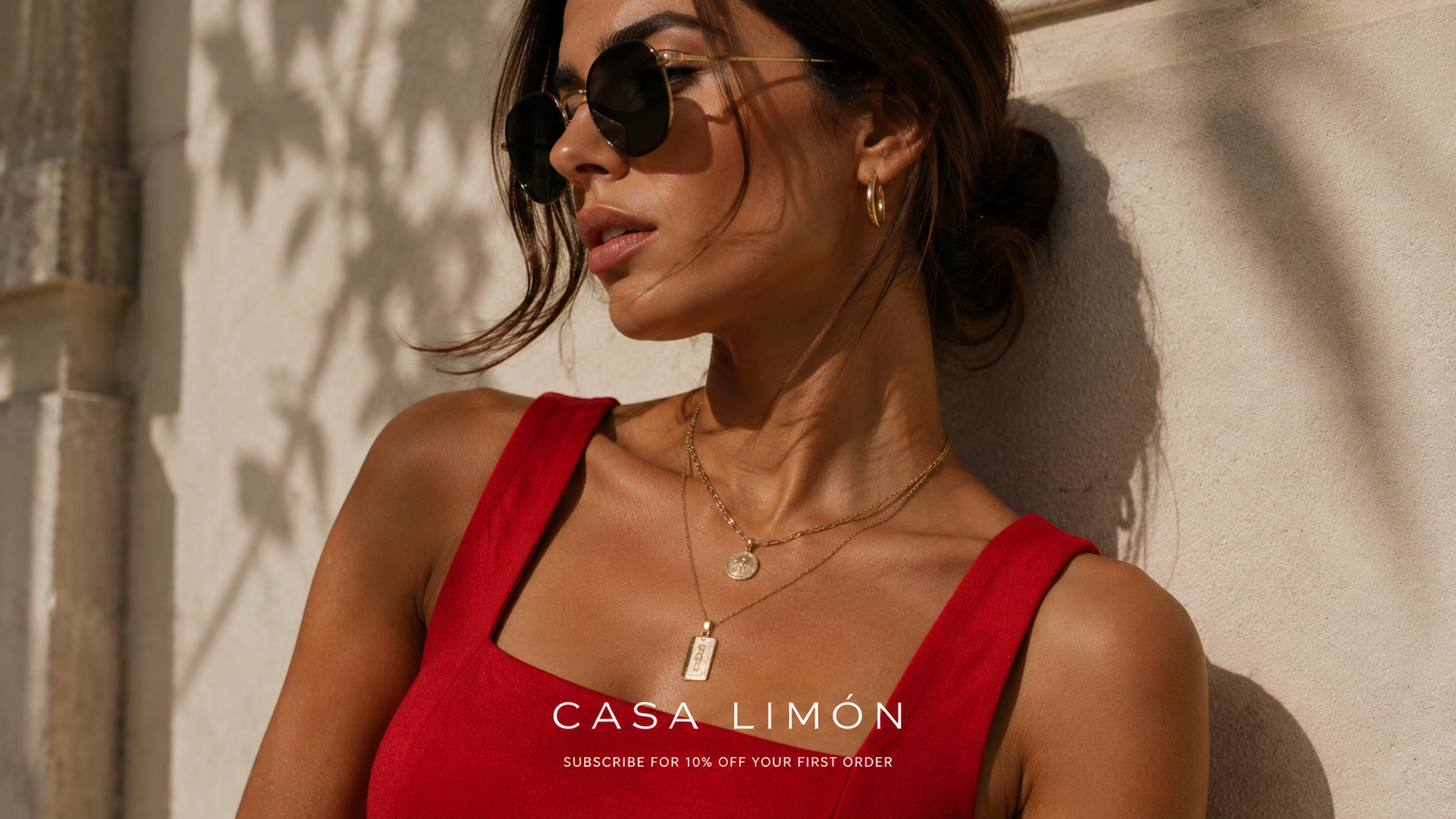Woman in a red dress with sunglasses against a beige wall, featuring Casa Limon branding.
