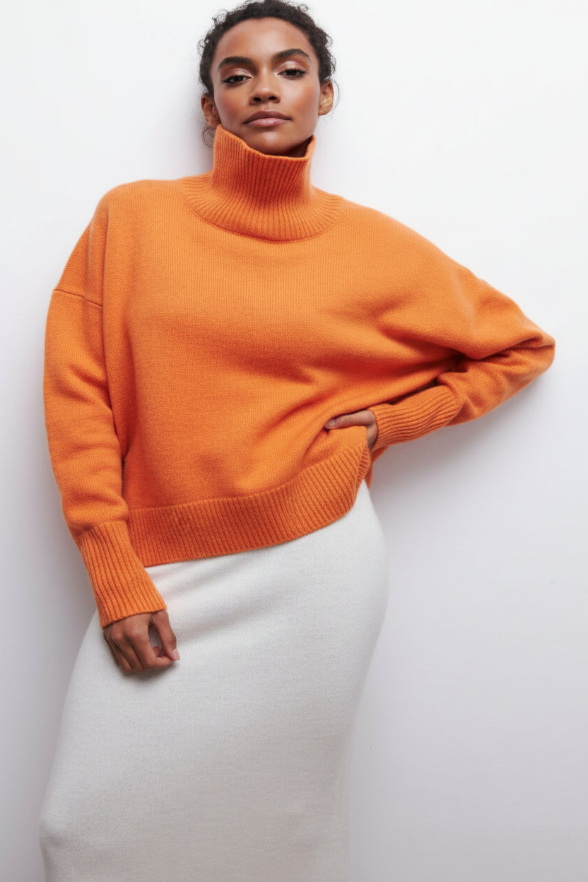 Person wearing an orange sweater and white pants against a light gray background
